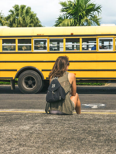 Girl sitting outside with school bus