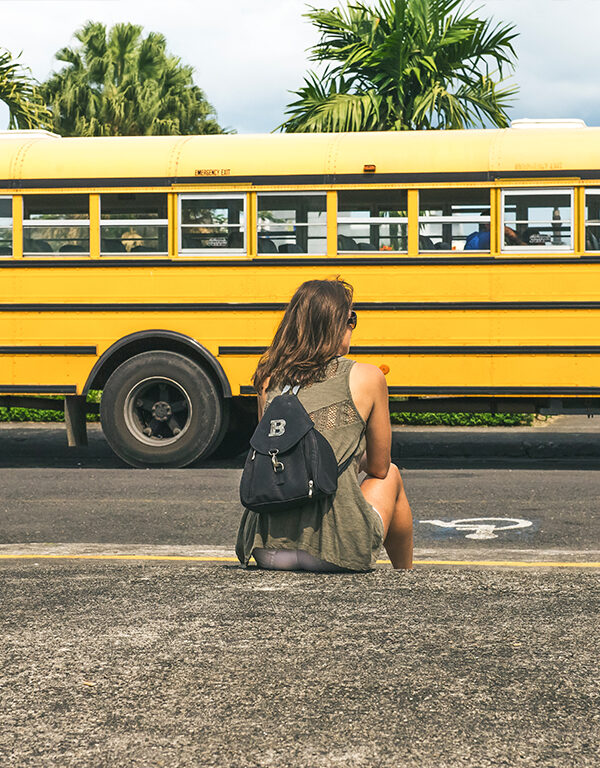 Girl sitting outside with school bus