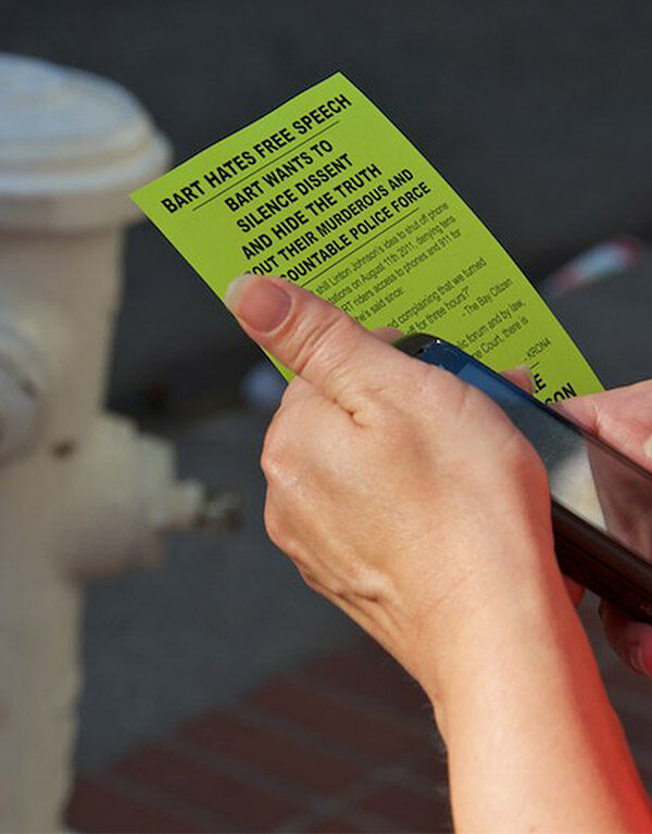 Person holding cell phone and flyer