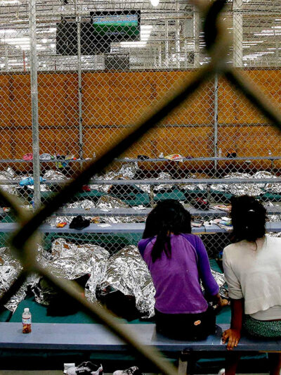 Two young girls watch a World Cup soccer match on a television from their holding area where hundreds of mostly Central American immigrant children are being processed and held
