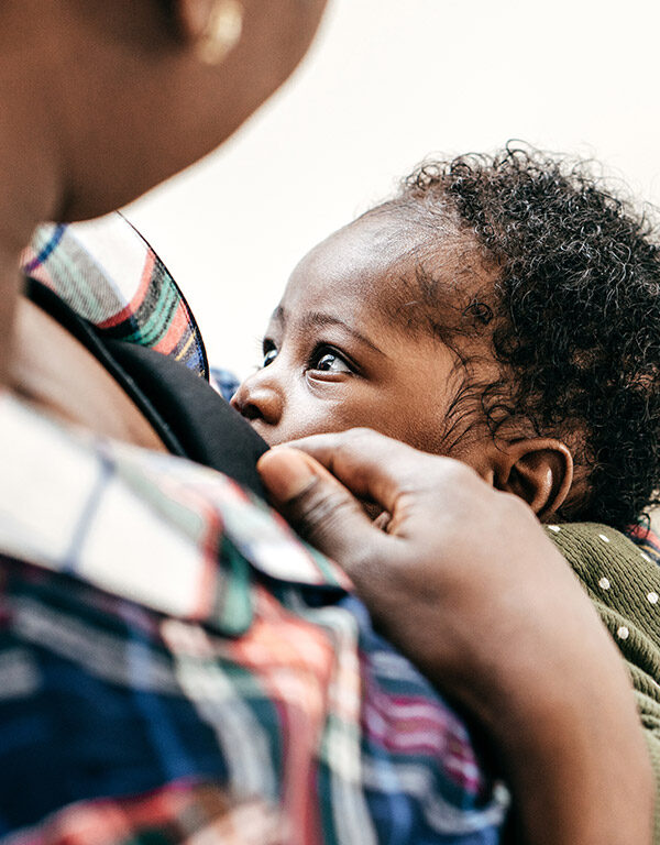 A Black person chest-feeding an infant