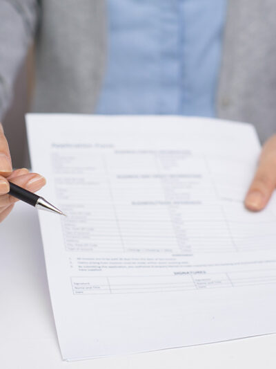 Image of a hand offering a pen to sign a document