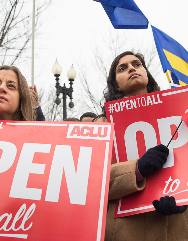 Demonstrators holding signs with the message 'Open to All"