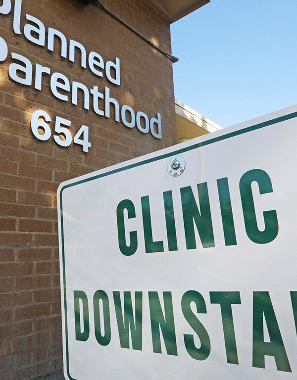 A sign with the text "Clinic Downstairs" outside a Planned Parenthood building