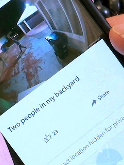 A person using the Ring smartphone app showing an image of two people in their backyard