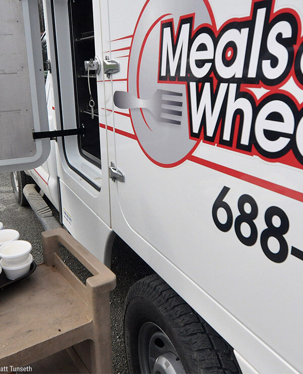 A Meals on Wheels driver loading food into a truck