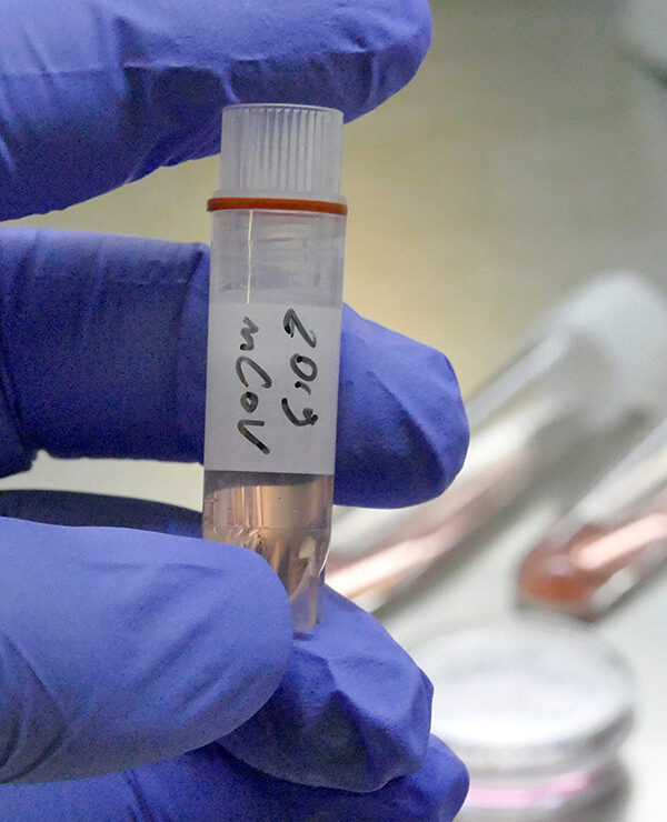 A gloved hand holding a vial of novel coronavirus 2019-nCoV in a laboratory.