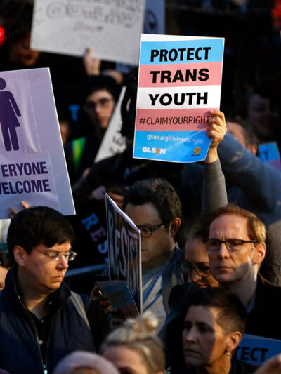 Protesters hold signs at a rally in support of transgender youth