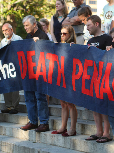 Protestors holding a banner that reads "Stop the Death Penalty" in front on Georgia's State Capital on a sunny day in 2017. Colorado just won a major feat for anti-death penalty movement with its decision to repeal the death penalty in the state.