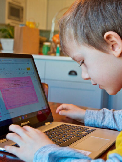 A young child works at home remotely on an online class assignment.
