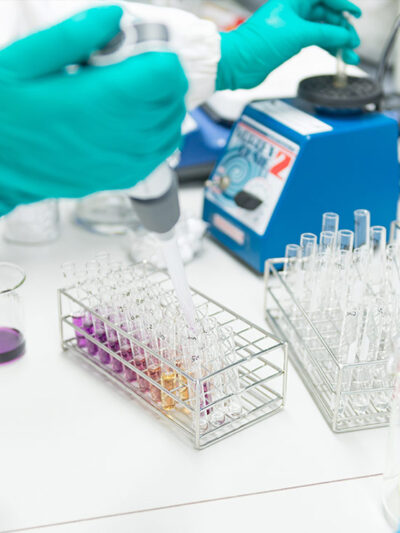 A gloved hand inject fluid into a test tube