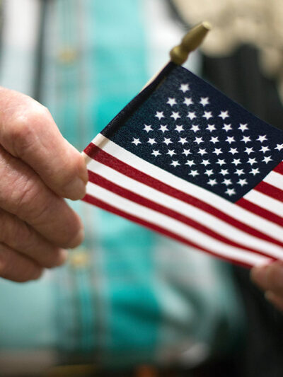 A man holding the American flag after a naturalization ceremony.