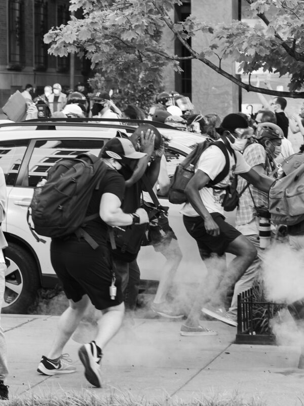 Black Lives Matter Protestors run as tear gas is dispensed into the crowd.