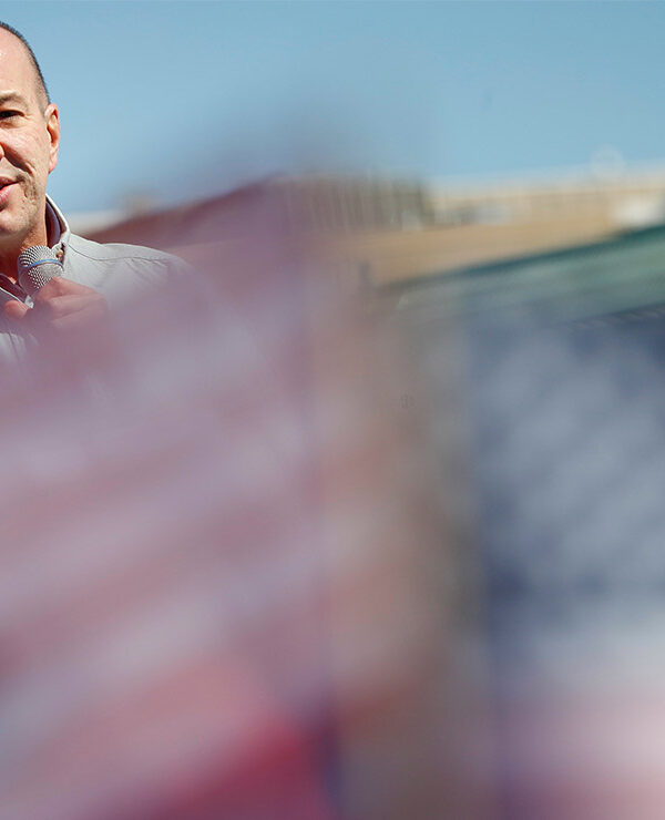 Anthony Romero speaks in the background while mini American flags wave blurred in the foreground.