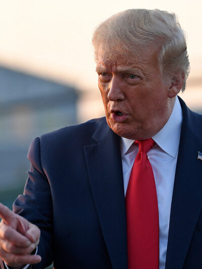 Trump wags finger as he talks to reporters before departing from a New Jersey airport.