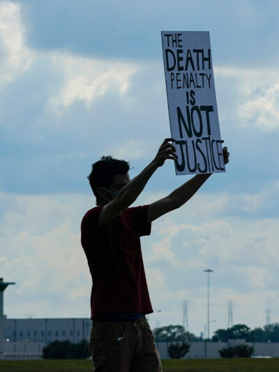 A death penalty protestor carries a sign that reads "the death penalty is not justice."