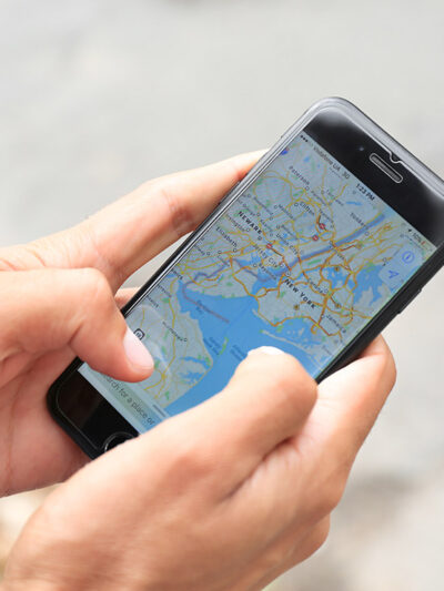 A man holding iPhone with navigation map app open on screen.