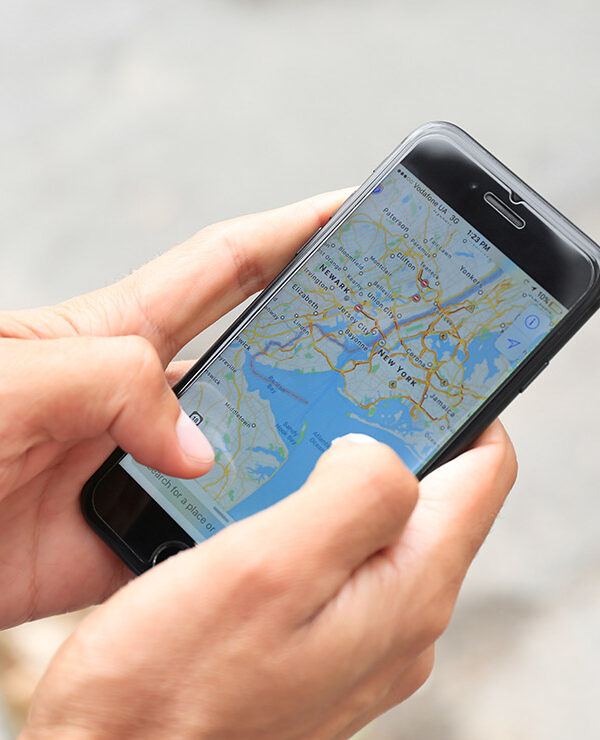 A man holding iPhone with navigation map app open on screen.