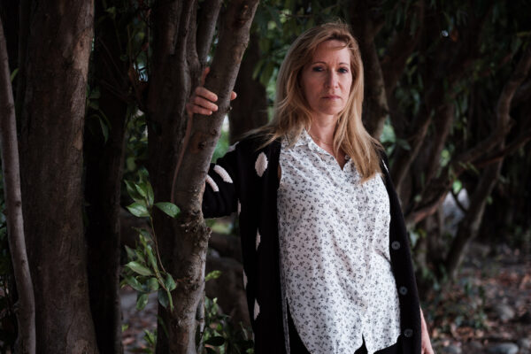Kristen DiAngelo, sex worker and activist, in white shirt standing with arm on a tree branch