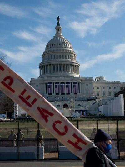 A man walks by the U.S. Capitol Building carrying a sign that reads "Impeach"