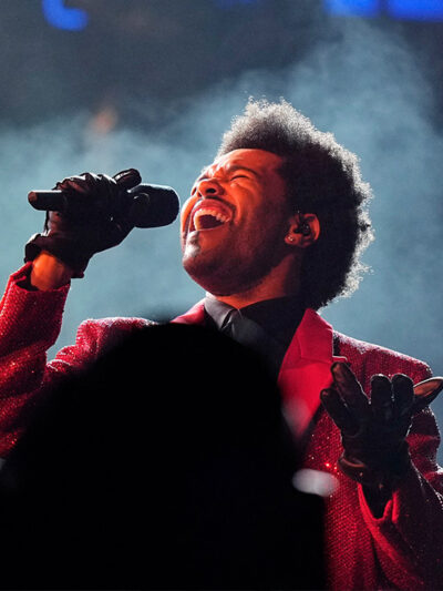 Artist The Weeknd sings into a microphone on stage at Super Bowl 55