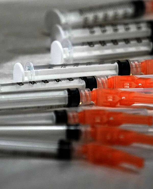 Syringes loaded with the Moderna COVID-19 Vaccine spread on a clinic table