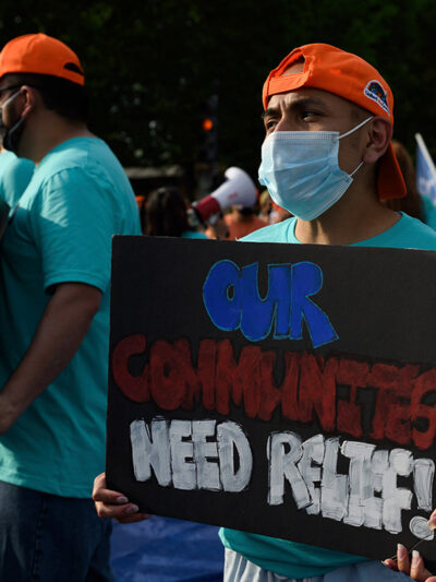 An activist holds sign that reads "Our Communities Need Relief" for immigration reform at a sit-in protest in downtown Washington, D.C.