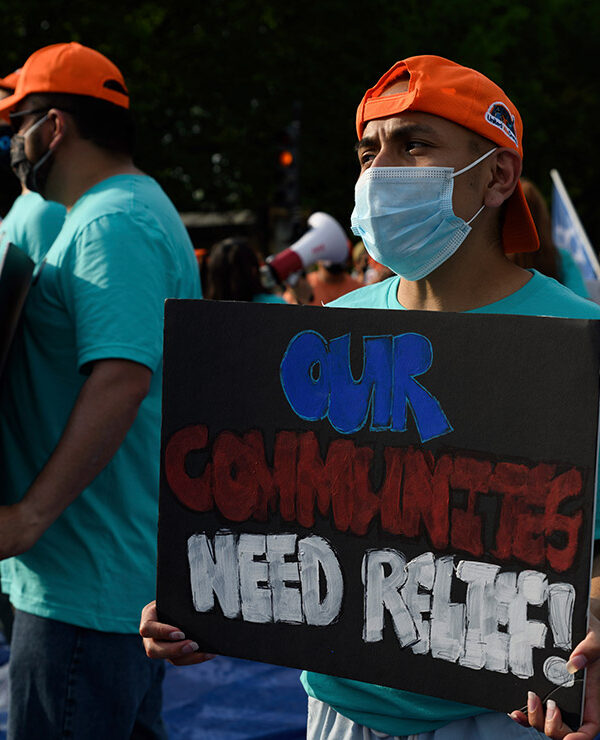 An activist holds sign that reads "Our Communities Need Relief" for immigration reform at a sit-in protest in downtown Washington, D.C.