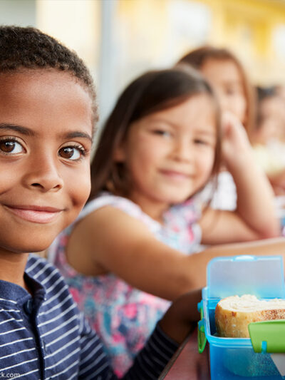 Young boy and girl sitting at a lunch table smiling at camera.