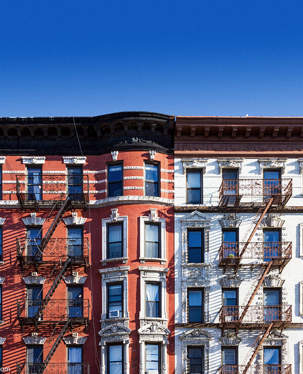 New York City block of old historic apartment buildings in the East Village of Manhattan, with clear blue sky background.
