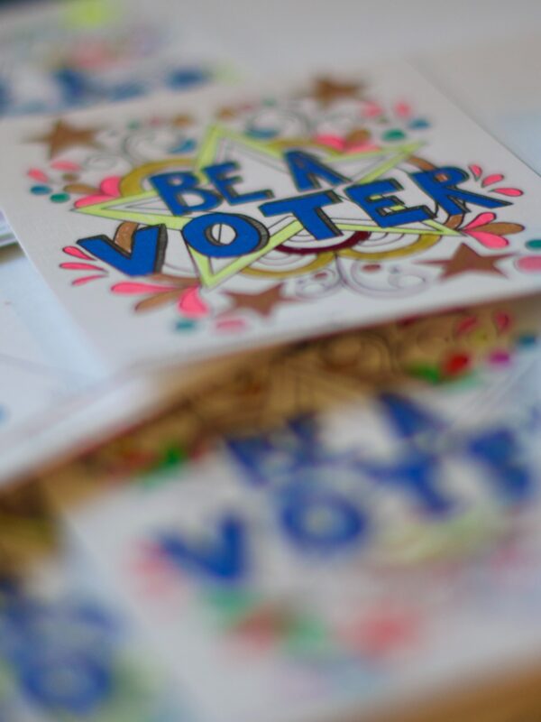 The words "Be a Voter" on a colorful sticker