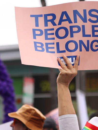 Someone holding a sign saying "Trans People Belong."