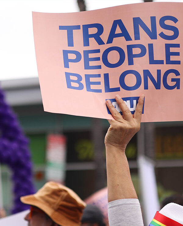 Someone holding a sign saying "Trans People Belong."