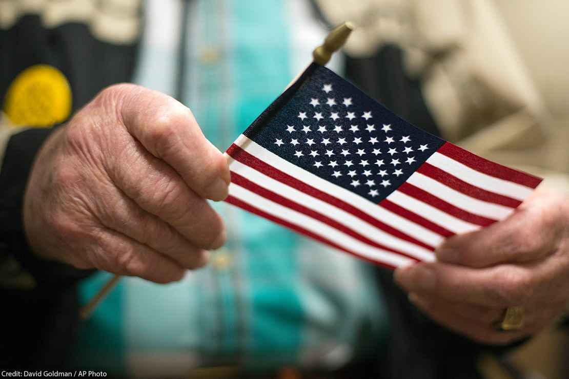 A man holding the American flag after a naturalization ceremony.