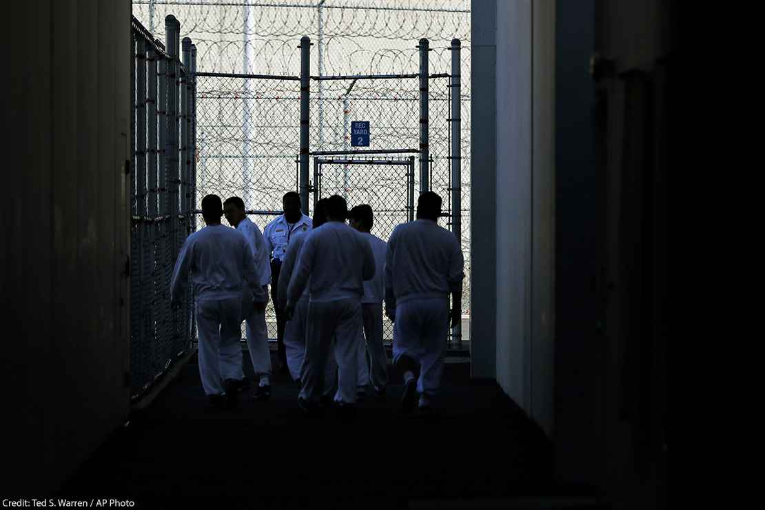 Detainees walk toward a fenced recreation area inside of an ICE detention facility in Washington state.