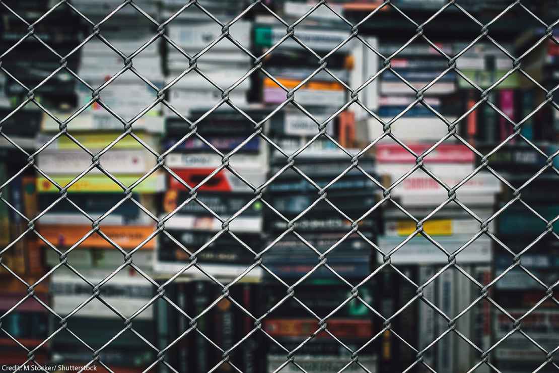 A stack of books behind a chain-link fence.