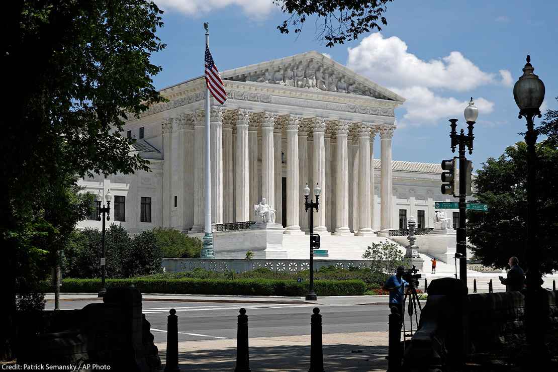 Photo of the American flag on a flag pole and the Supreme Court in Washington, DC.