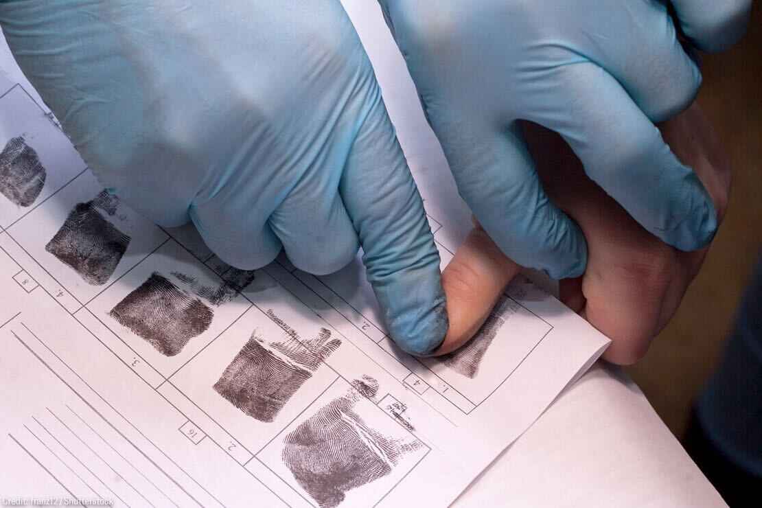 crime investigator wearing gloves fingerprinting person