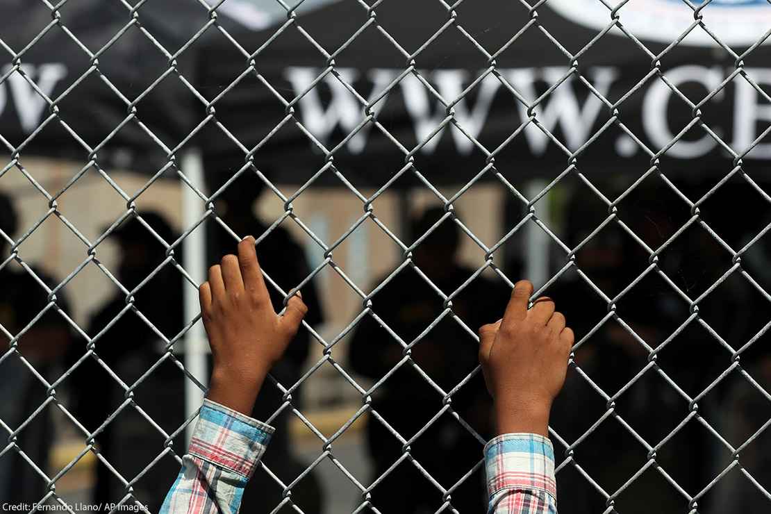 A migrant leans on a fence of the Gateway International Bridge that connects downtown Matamoros, Mexico with Brownsville, Texas.