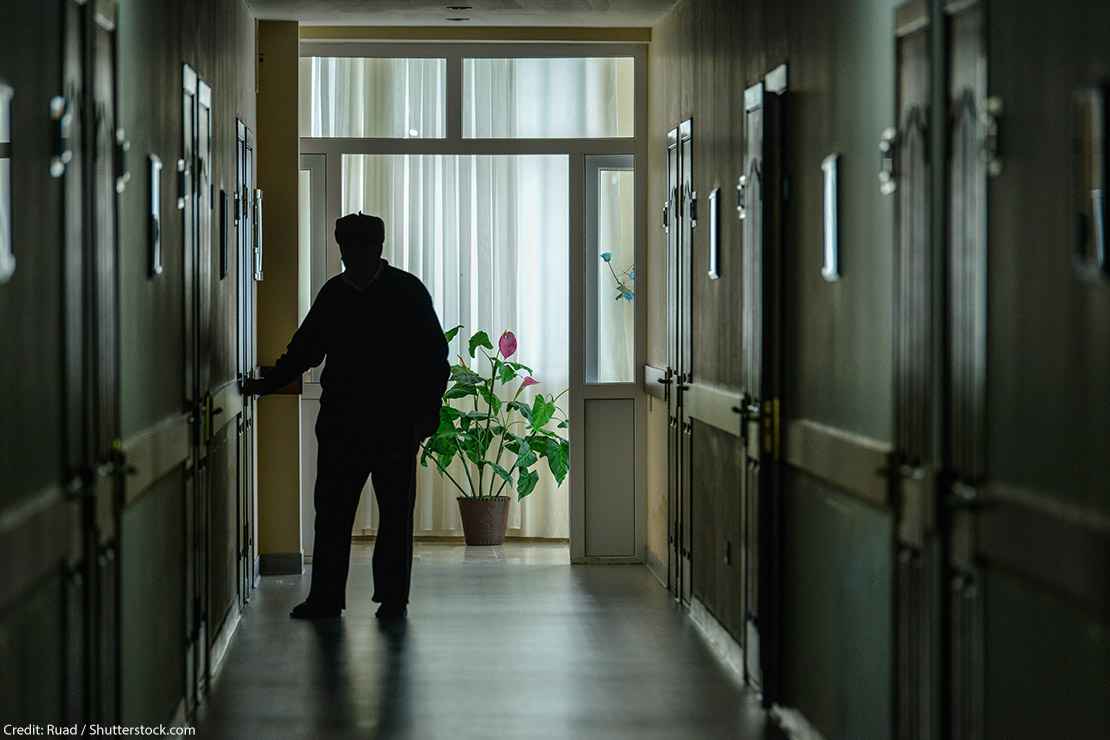 A resident walks down the darkened hall of a nursing home.