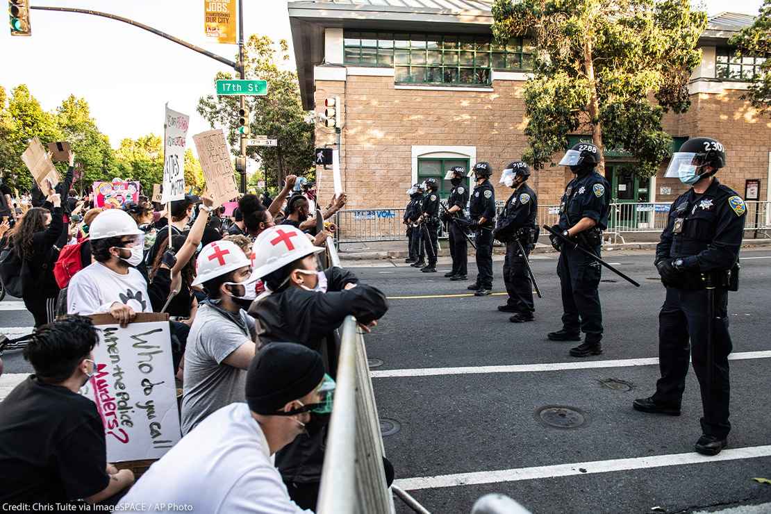 Protestors demonstrate in front of a line of police officers outside of Mission Police Station in San Francisco after the death of George Floyd