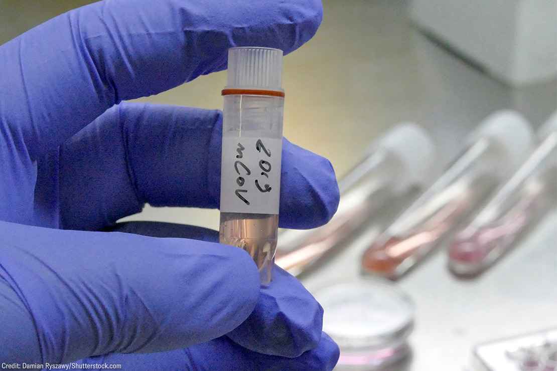 A gloved hand holding a vial of novel coronavirus 2019-nCoV in a laboratory.