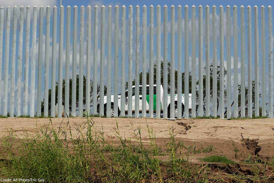 A CBP truck is seen through a border wall