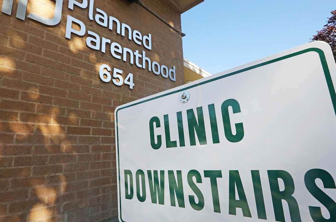 A sign with the text &quot;Clinic Downstairs&quot; outside a Planned Parenthood building