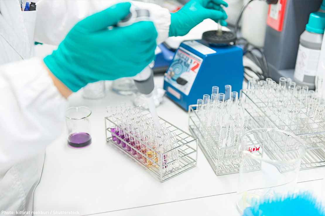 A gloved hand inject fluid into a test tube