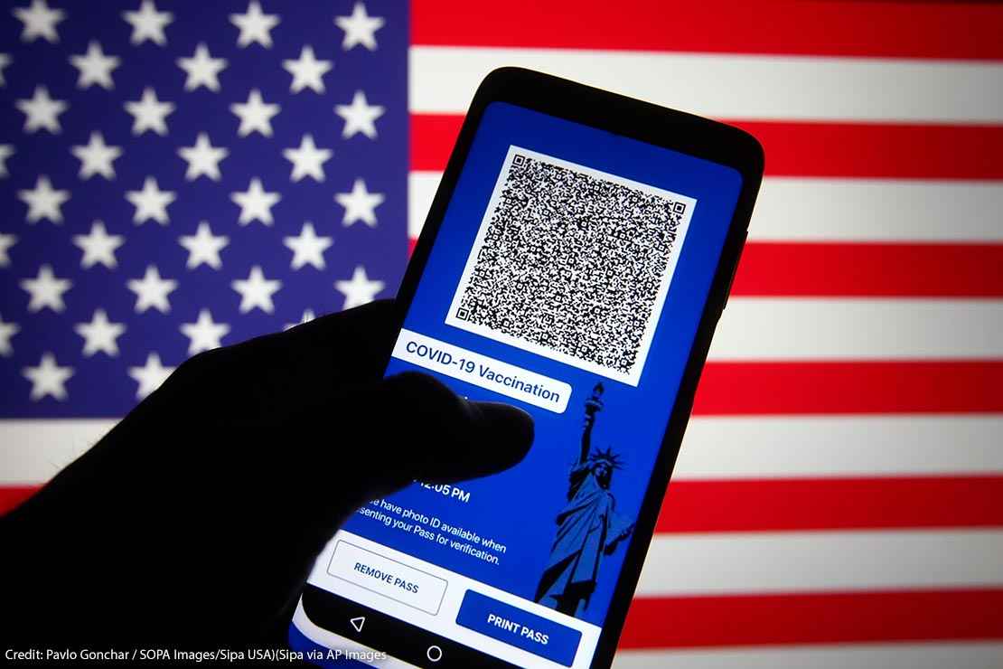 In this photo illustration, Excelsior Pass app which provides digital proof of COVID-19 vaccination or negative test results seen displayed on a smartphone screen in front of the US flag.