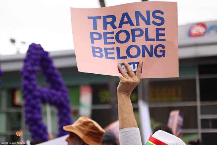 Someone holding a sign saying "Trans People Belong."